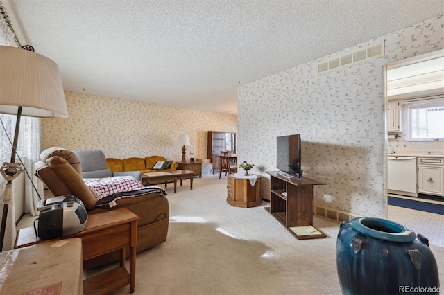 living area with wallpapered walls, visible vents, and a textured ceiling