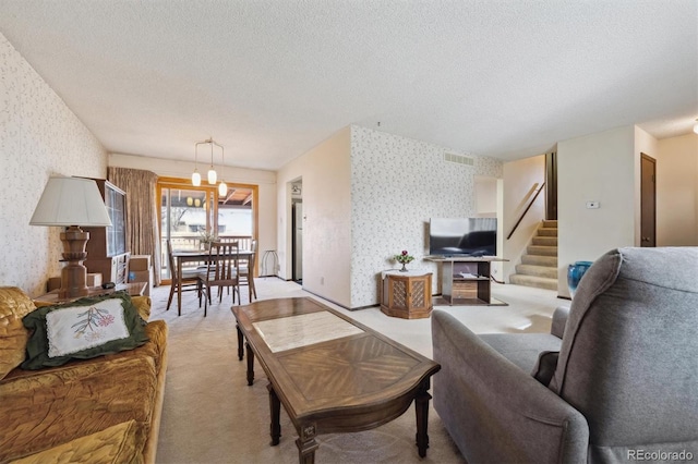 living area with baseboards, wallpapered walls, stairs, a textured ceiling, and light carpet