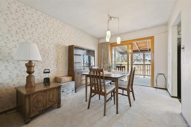 dining space featuring wallpapered walls, light colored carpet, baseboards, and a textured ceiling