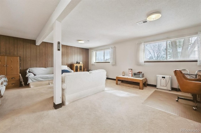 carpeted bedroom featuring visible vents, baseboards, beamed ceiling, wood walls, and a textured ceiling