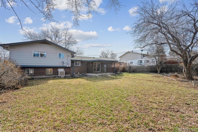 back of house featuring brick siding, fence, central air condition unit, a lawn, and a sunroom