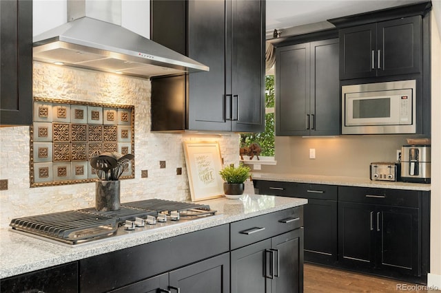 19429 W 88th Dr, Arvada, CO 80007 - kitchen with wall chimney range hood, appliances with stainless steel finishes, backsplash, and dark cabinets
