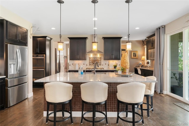 19429 W 88th Dr, Arvada, CO 80007 - kitchen with appliances with stainless steel finishes, backsplash, a center island with sink, light stone counters, and dark wood-style flooring