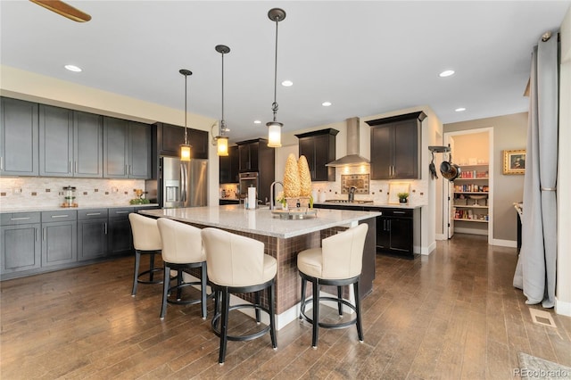 19429 W 88th Dr, Arvada, CO 80007 - kitchen featuring wall chimney range hood, appliances with stainless steel finishes, backsplash, dark wood-style floors, and recessed lighting