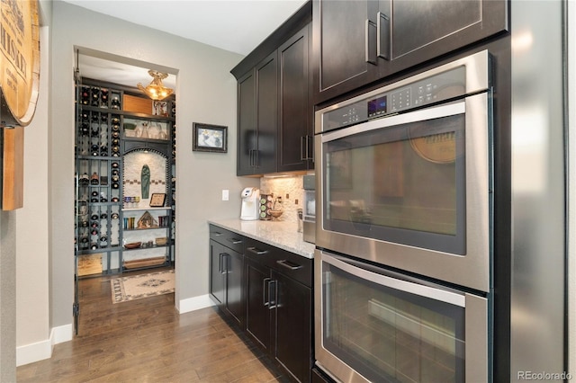 19429 W 88th Dr, Arvada, CO 80007 - bar featuring stainless steel double oven, dark wood-type flooring, and backsplash