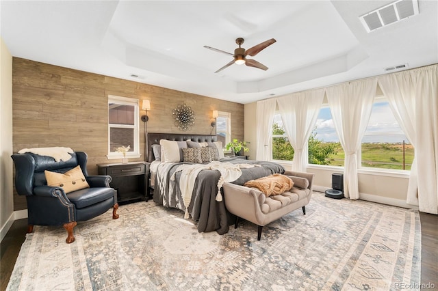19429 W 88th Dr, Arvada, CO 80007 - bedroom with a raised ceiling, wooden walls, wood finished floors, and ceiling fan