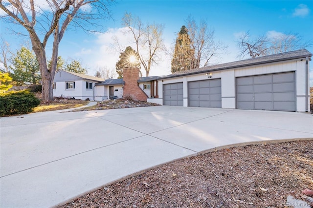 view of front of house featuring a garage, concrete driveway, and a chimney