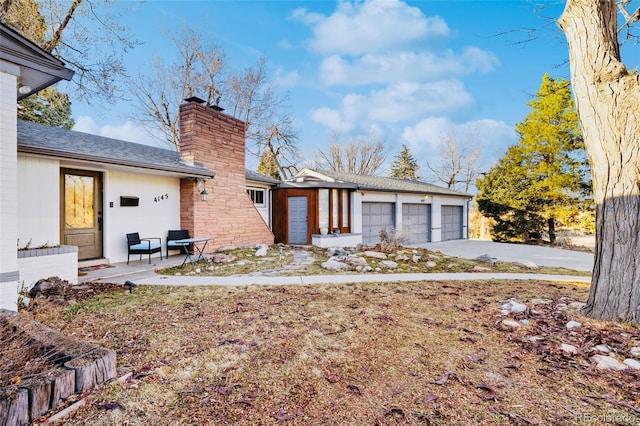 view of front of property with a garage, a chimney, and an outbuilding