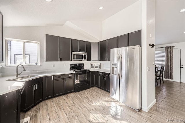 kitchen featuring stainless steel appliances, lofted ceiling, and sink