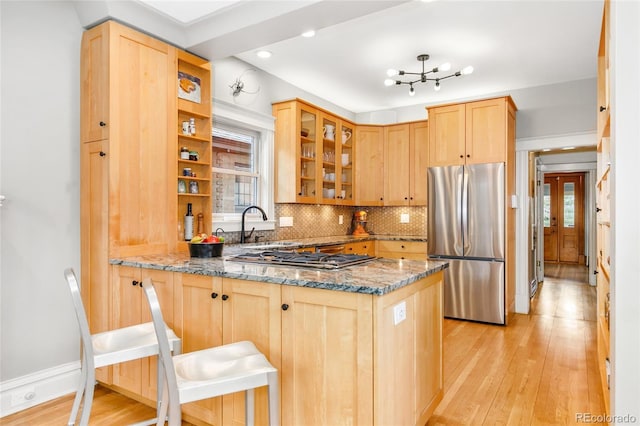 3701 Eliot St, Denver, CO 80211 - kitchen featuring appliances with stainless steel finishes, stone countertops, a peninsula, light brown cabinetry, and light wood finished floors