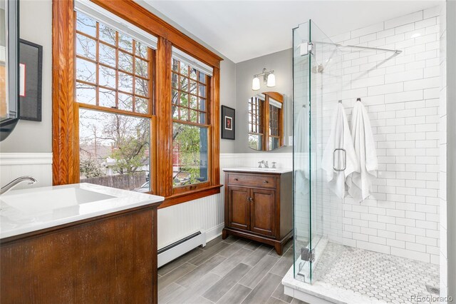 3701 Eliot St, Denver, CO 80211 - bathroom with a baseboard radiator, vanity, a stall shower, wainscoting, and wood finished floors