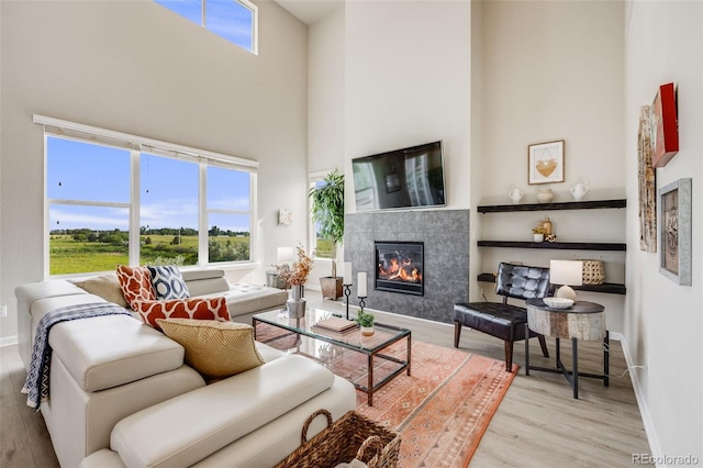 3620 Sandoval St, Brighton, CO 80601 - living area with a tiled fireplace, wood finished floors, a high ceiling, and plenty of natural light