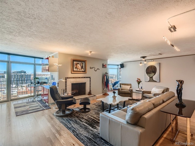 living room featuring floor to ceiling windows, hardwood / wood-style floors, a textured ceiling, and a fireplace