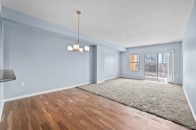 interior space featuring baseboards, an inviting chandelier, and wood finished floors