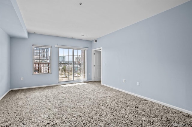 carpeted empty room featuring baseboards and visible vents