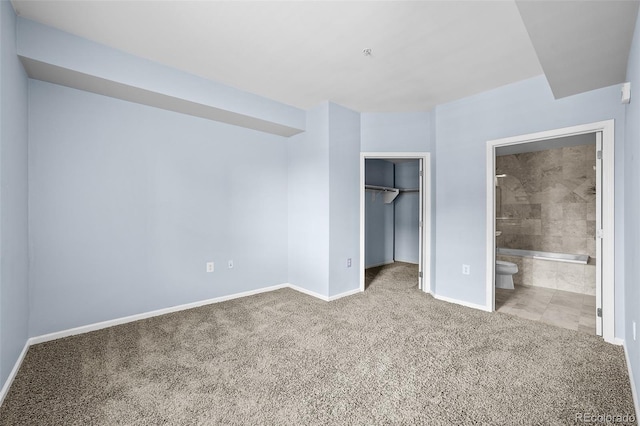 unfurnished bedroom featuring a closet, a spacious closet, carpet floors, connected bathroom, and baseboards
