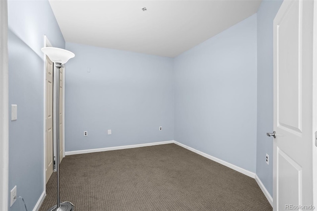 empty room with baseboards and dark carpet