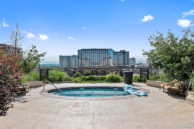 view of pool featuring a patio area, a swimming pool, a view of city, and fence