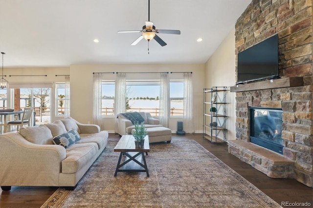 living room with ceiling fan, a fireplace, and dark wood-type flooring