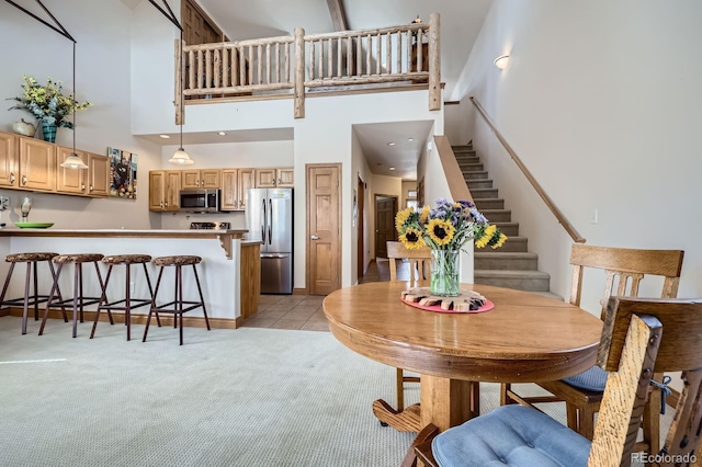 846 Blue River Pkwy Unit C2, Silverthorne, CO 80498 - dining area featuring light tile patterned flooring, light colored carpet, stairs, and a towering ceiling