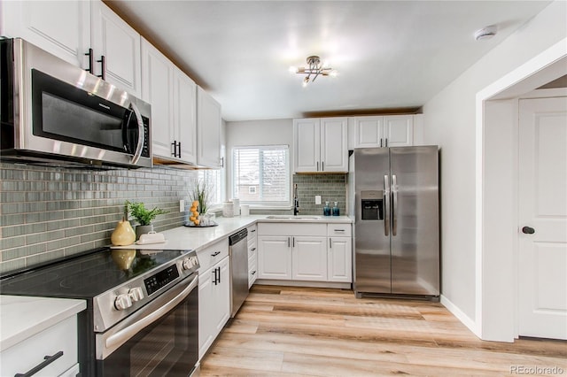 kitchen with sink, white cabinetry, light hardwood / wood-style flooring, stainless steel appliances, and decorative backsplash