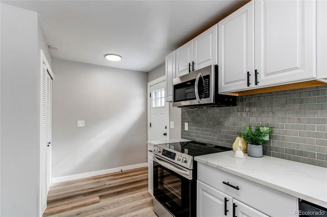 kitchen with stainless steel appliances, light stone countertops, decorative backsplash, and white cabinets