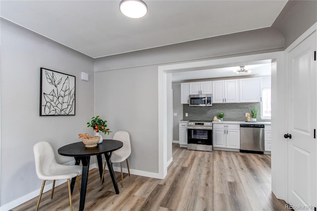 kitchen with stainless steel appliances, light hardwood / wood-style flooring, white cabinets, and decorative backsplash