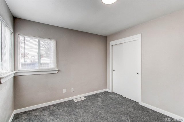 unfurnished bedroom featuring dark carpet and a closet