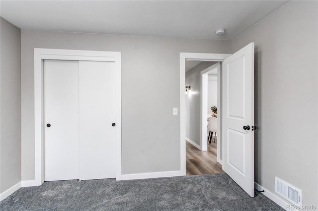 unfurnished bedroom with dark carpet and a closet