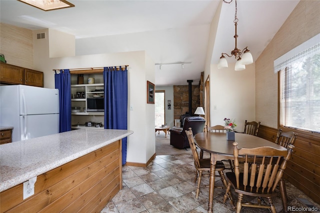 29101 Drexel Spur, Evergreen, CO 80439 - dining space with a wood stove, a chandelier, lofted ceiling, rail lighting, and light stone finish floors