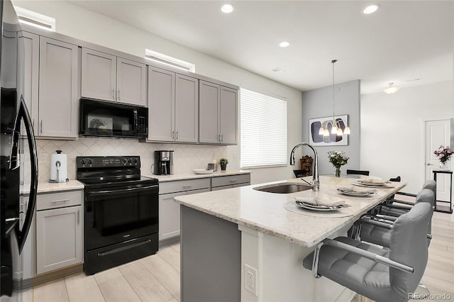 12258 Hazel Spruce Ct, Parker, CO 80134 - kitchen featuring black appliances, a sink, gray cabinets, light stone counters, and decorative backsplash