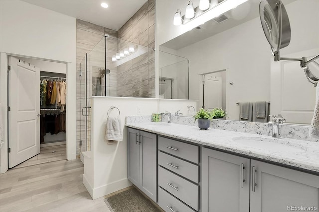 12258 Hazel Spruce Ct, Parker, CO 80134 - bathroom featuring a shower stall, wood finished floors, double vanity, baseboards, and recessed lighting