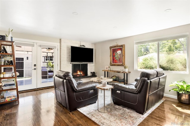 living room featuring hardwood / wood-style flooring, a large fireplace, and french doors