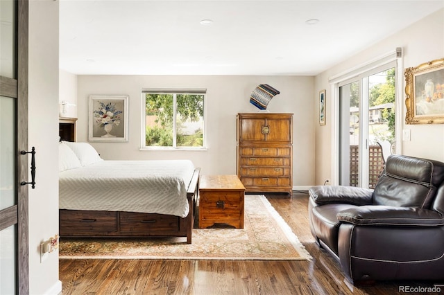 bedroom with multiple windows, dark wood-type flooring, and access to outside