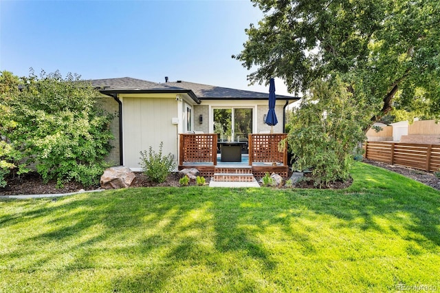 rear view of property featuring a wooden deck and a yard