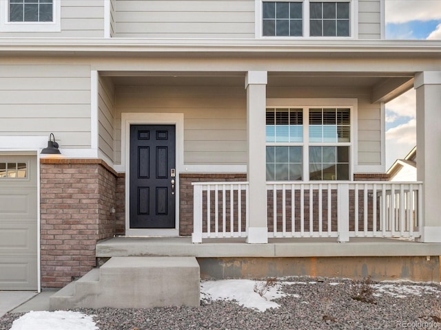 snow covered property entrance featuring a porch