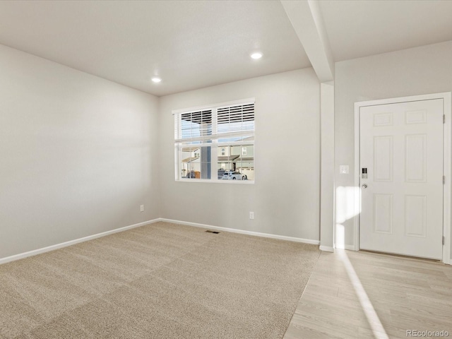 entrance foyer with light colored carpet and beam ceiling