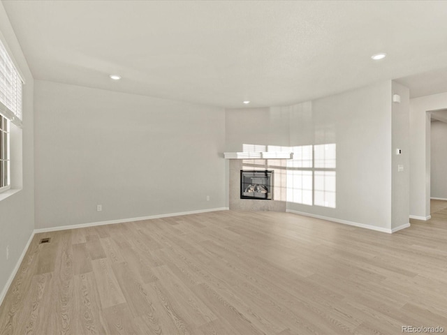 unfurnished living room featuring a tile fireplace and light hardwood / wood-style flooring