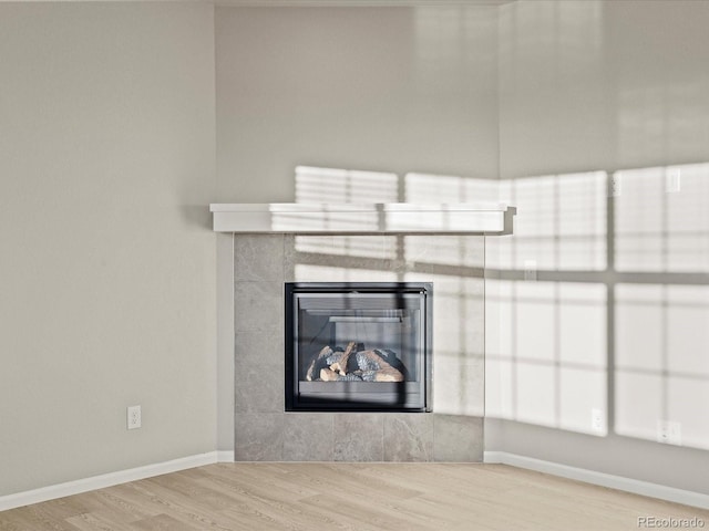 room details featuring wood-type flooring and a tile fireplace