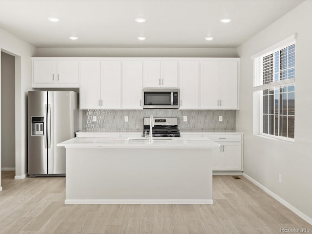 kitchen featuring a center island with sink, appliances with stainless steel finishes, light hardwood / wood-style flooring, and white cabinets