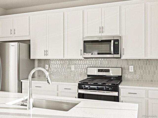 kitchen with stainless steel appliances, backsplash, white cabinets, and sink