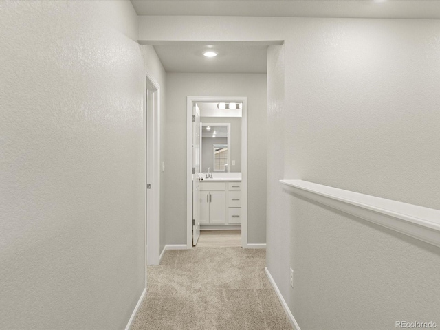 corridor featuring light colored carpet and sink