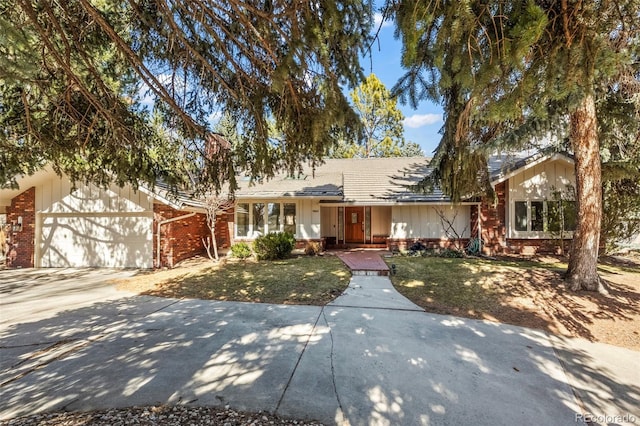 ranch-style home featuring brick siding, an attached garage, driveway, and a front lawn