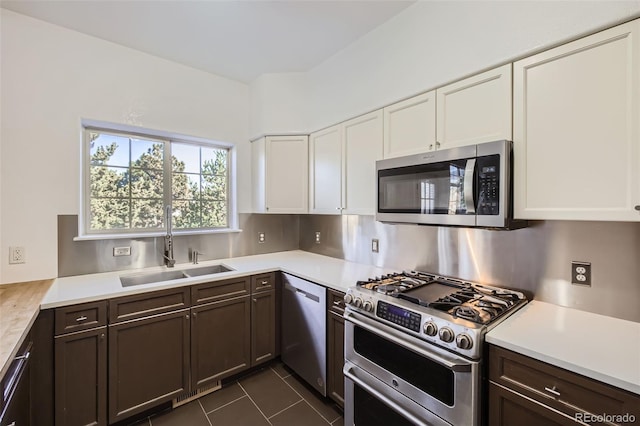 kitchen featuring appliances with stainless steel finishes, sink, white cabinets, dark tile patterned floors, and dark brown cabinets