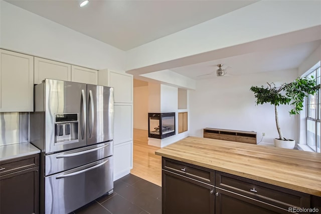 kitchen featuring stainless steel refrigerator with ice dispenser, ceiling fan, white cabinets, and butcher block countertops