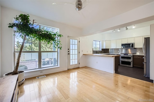 kitchen with stainless steel appliances, white cabinetry, light wood-type flooring, and kitchen peninsula