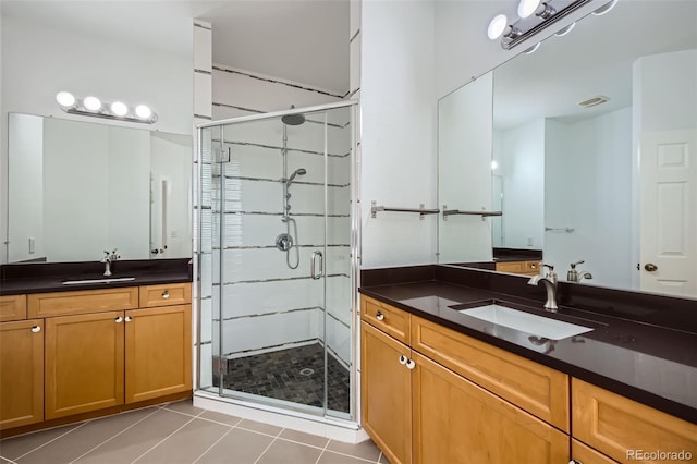 bathroom with a shower with door, vanity, and tile patterned floors