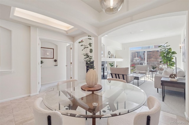 dining space with arched walkways, light tile patterned floors, and baseboards