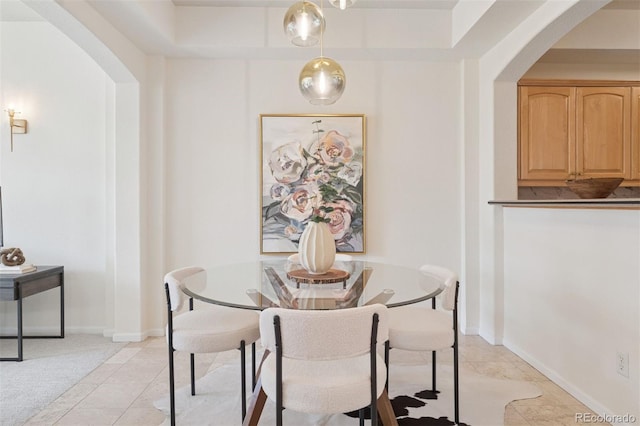 dining room featuring arched walkways and light tile patterned floors