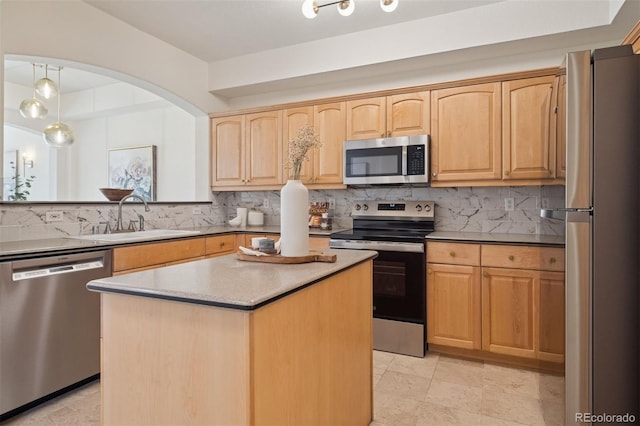 kitchen with stainless steel appliances, a sink, decorative backsplash, light brown cabinets, and a kitchen island